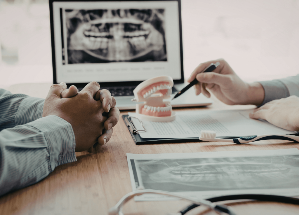 Dentist explaining denture treatment using model and X-ray during consultation